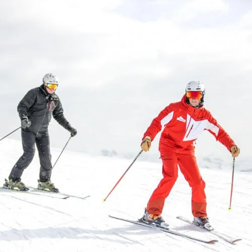 Zwei Skifahrer im Unterricht auf der Piste in den Bergen