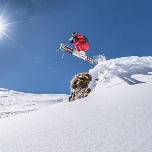 Skiurlauber springt im Schnee mit klarem Himmel