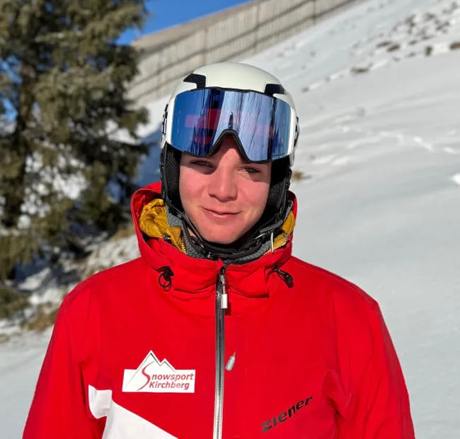 Junger Skifahrer in roter Jacke im Schnee