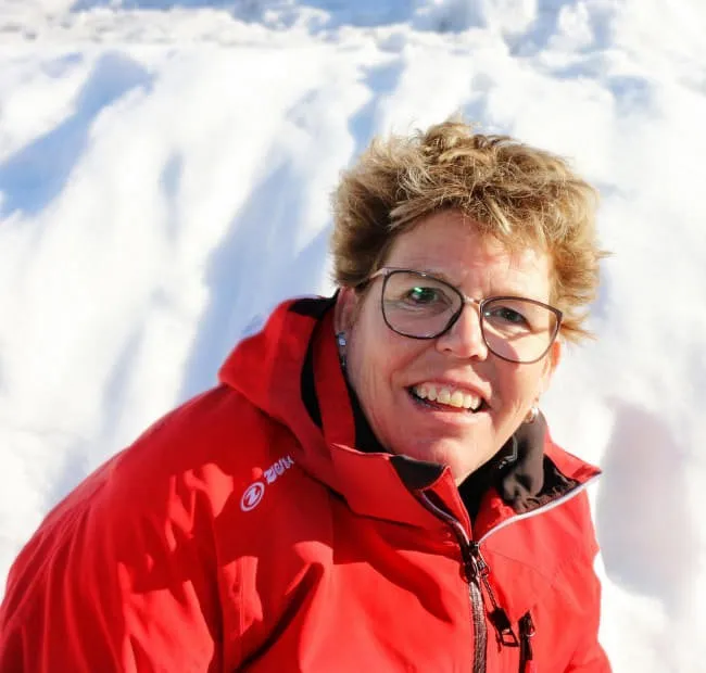 Person in roter Jacke lächelt im Schnee