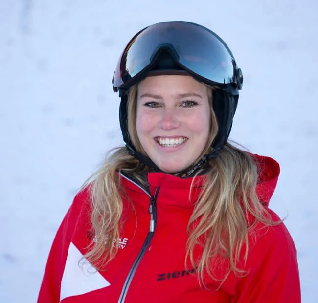 Lächelnde Skifahrerin in roter Kleidung mit Skibrille draußen