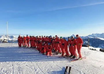 Gruppe von Skifahrern in roten Anzügen auf dem Schnee