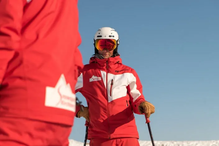 Skilehrer in roten Anzügen auf Schnee.